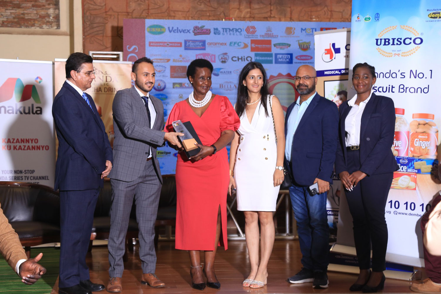 Dembe Trading Enterprises Limited managing director Mr. Aditya and team receiving the East Africa Brand Quality from Hon. Amelia Kyambadde Dembe Trading Enterprises Limited managing director Mr. Aditya and team receiving the East Africa Brand Quality from Hon. Amelia Kyambadde